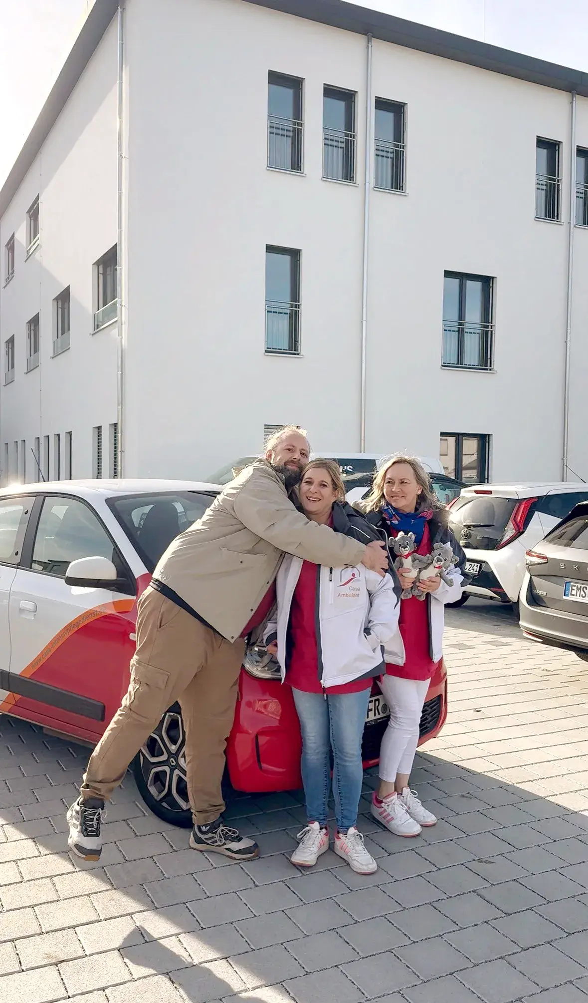 Drei Mitarbeitende von Casa Ambulant stehen gemeinsam vor einem Dienstfahrzeug.